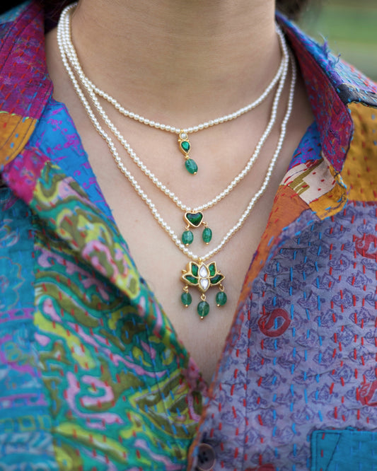 Three-layered 925 silver pearl necklace with emerald heart detail and lotus-inspired kundan pendant with green stone drops.