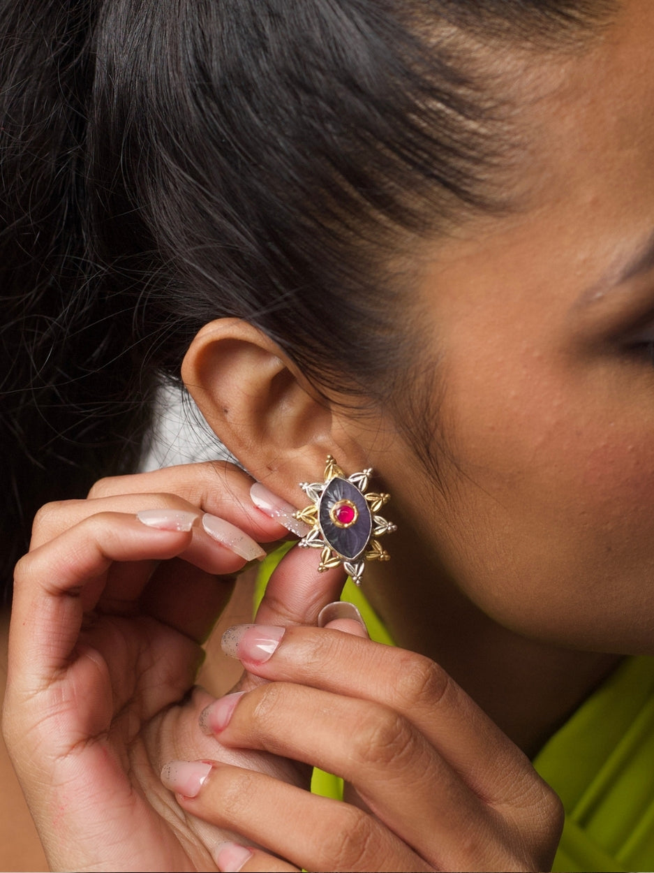 Close-up of dual-tone eye-shaped silver stud with red centre and star-shaped gold detailing from Naksa