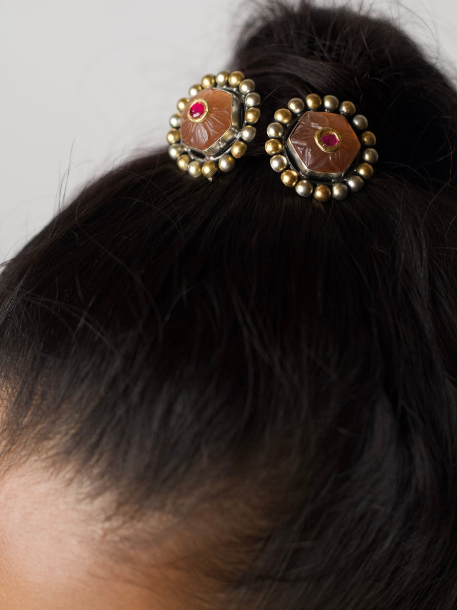 Close-up of handmade 925 silver Mango Pudding Studs with golden and silver beaded frame and pink crystal centre on green fabric.