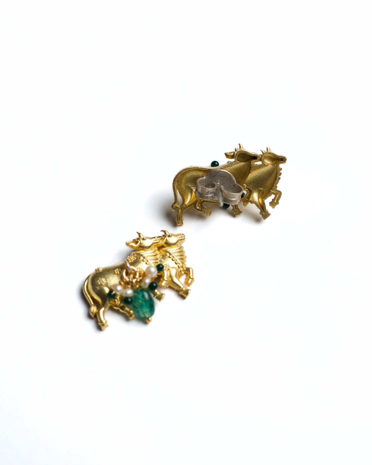 Close-up of gold-polished 925 silver cow motif stud earrings with pearl clusters and green stone drops on a white background.