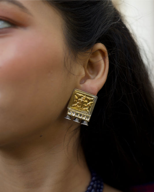 Square 925 silver stud earrings with gold polish, embossed floral motif, kundan-style stone row and small oxidised ghungroo drops from Naksa Playround collection.