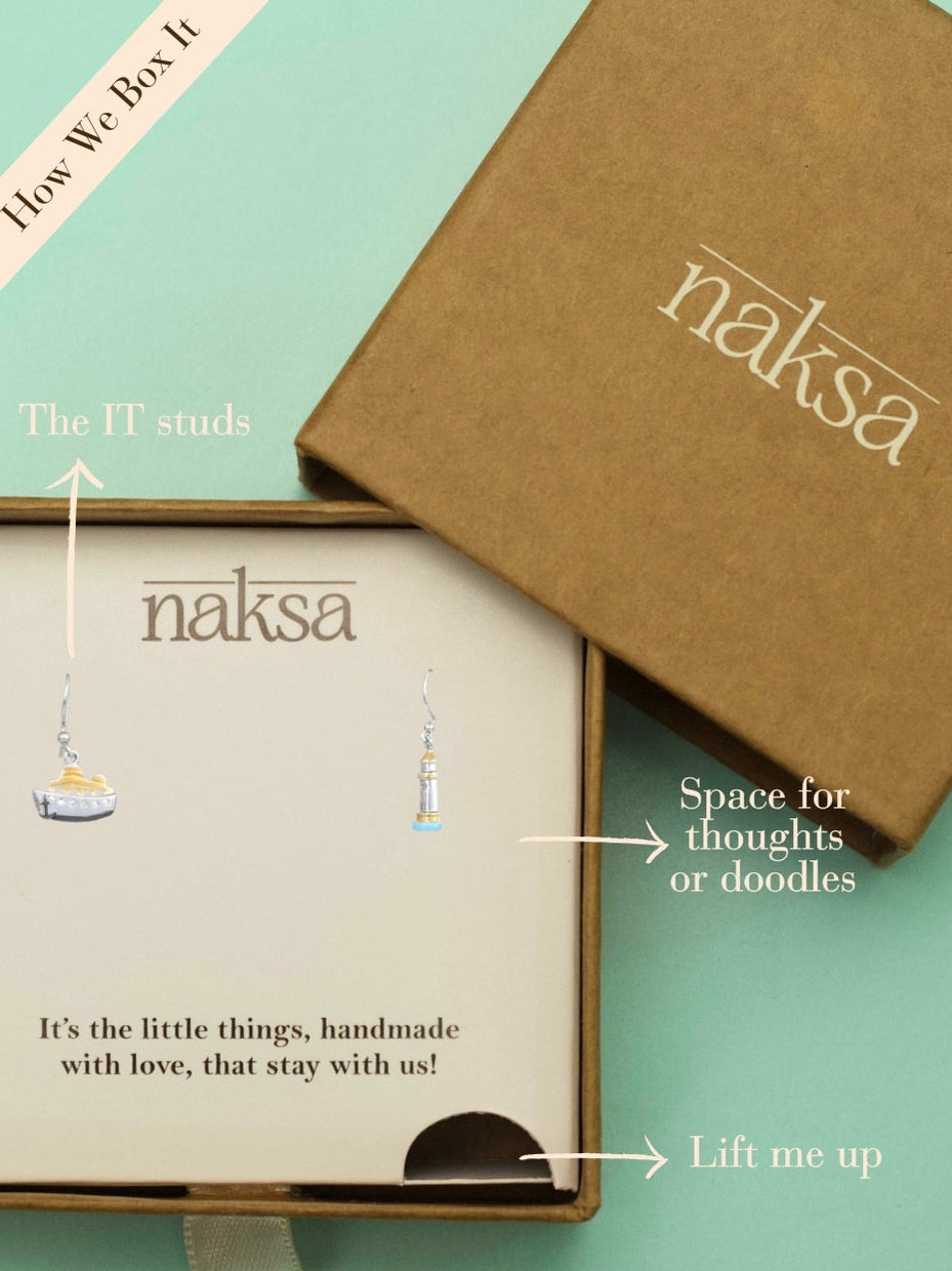 Sail & Stay Danglers by Naksa—mismatched nautical earrings featuring a ship and lighthouse in hand-enameled 925 silver with gold and blue accents.