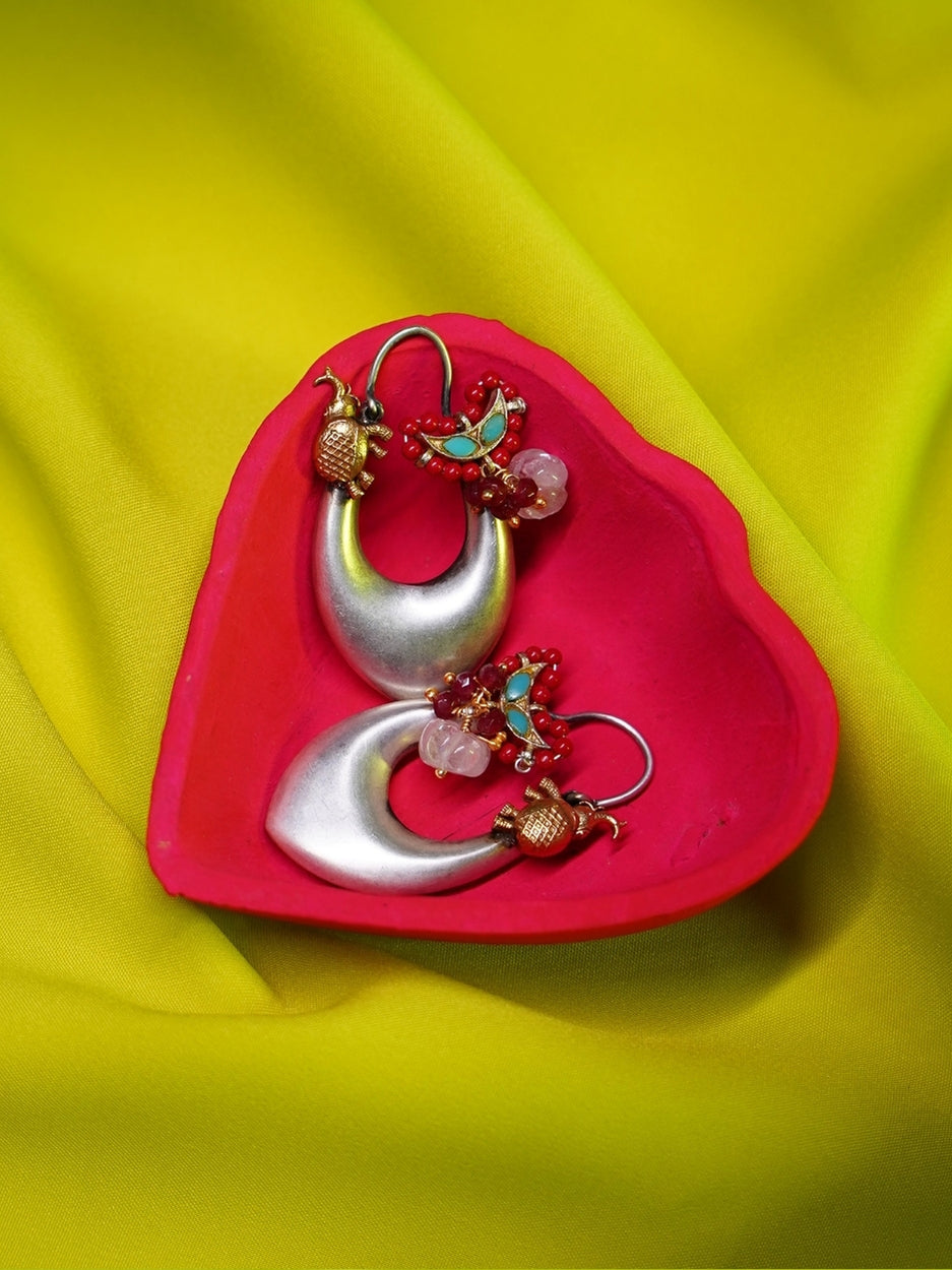 Elongated heart-shaped silver hoop earrings with golden elephant motifs, red beads, turquoise accents, and a white gemstone – Naksa
