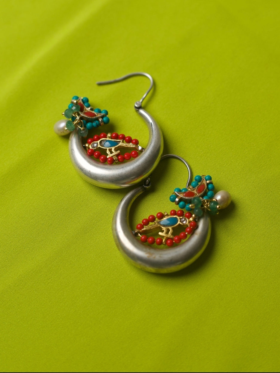 Pair of circular 92.5 silver hoop earrings with gold parrot motif, red and turquoise beads, pearl accent, and enamel detail