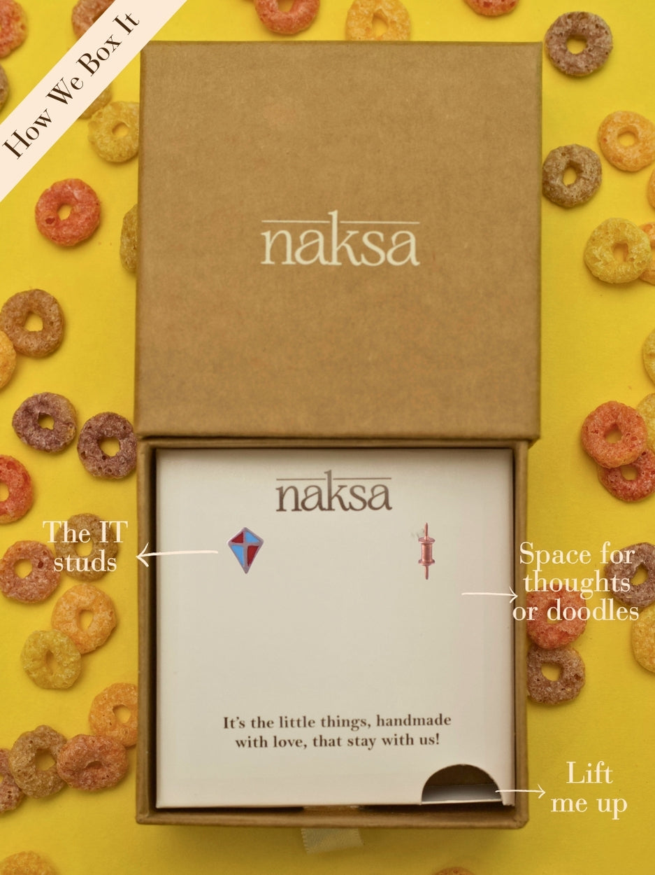 Sky High Baes Studs by Naksaâmismatched kite and spool earrings in 92.5 silver with red and blue enamel detailing, celebrating childhood memories.