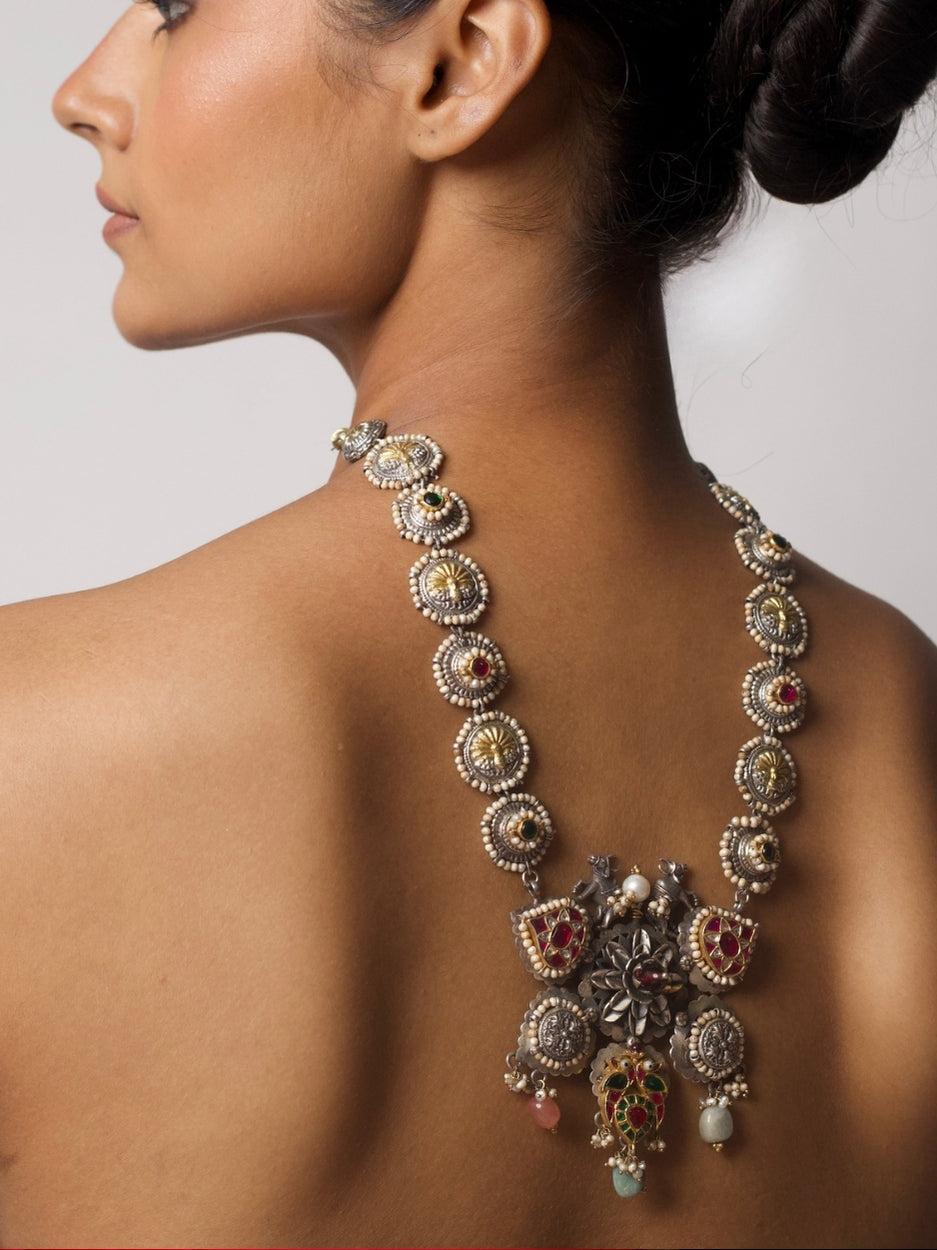 Cows in the Garden Haar, a handcrafted silver necklace featuring cow motifs, floral details, pearls, and multicoloured tikris in gold, green, and pink accents.