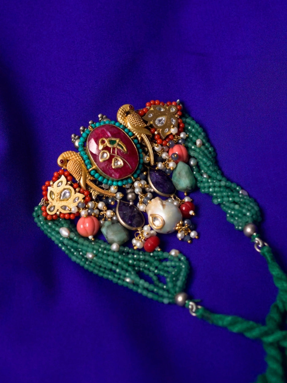 Close-up of Jewel of the Court Choker in 92.5 silver with parrot motifs, carved red center stone, kundan accents, coral and pearl drops