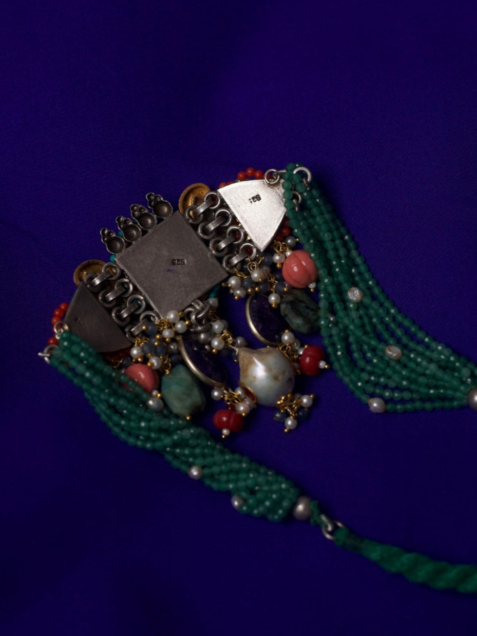 Close-up of Jewel of the Court Choker in 92.5 silver with parrot motifs, carved red center stone, kundan accents, coral and pearl drops