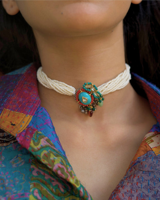 Multi-strand pearl choker with turquoise circular centre, teardrop kundan stone, red bead halo and green stone accents in 925 silver with gold polish.