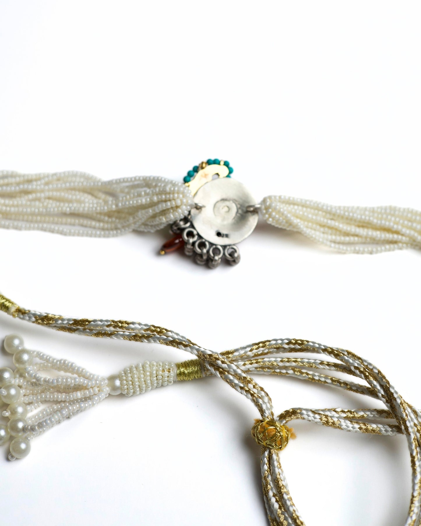 Multi-strand pearl choker with turquoise circular centre, teardrop kundan stone, red bead halo and green stone accents in 925 silver with gold polish.