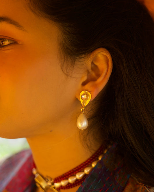 Close-up of gold-polished 925 silver drop earrings featuring a faceted clear stone stud and a suspended white teardrop pearl.