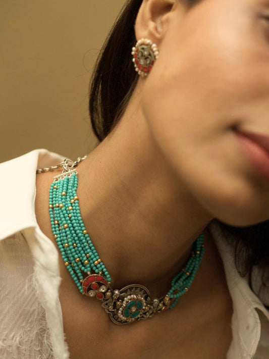 Saffron Skies Choker Set in pure 925 silver with layered firozi stones, orange tikras, angel motifs, and pearl drop earrings by Naksa.