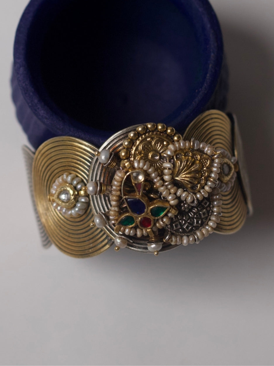 Handcrafted silver cuff with spiral base, navratna enamel, and sculptural motifs in 92.5 silver by Naksa