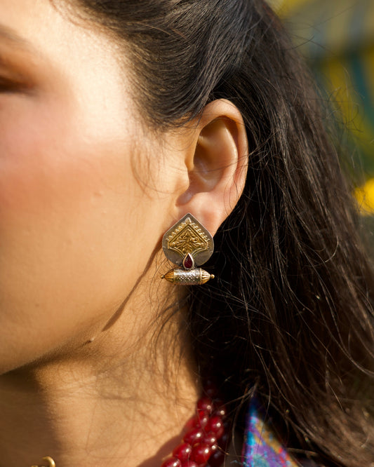 Spade-shaped 925 silver gold-polished stud earrings with engraved detailing and central ruby-toned teardrop accent.