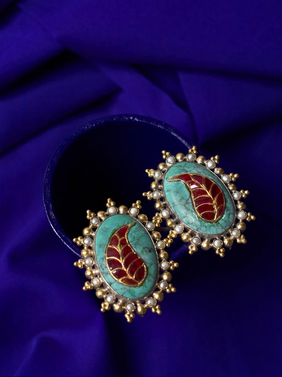 Close-up of a bold handcrafted 92.5 silver stud earring with red enamel leaf on turquoise stone, framed with pearls.