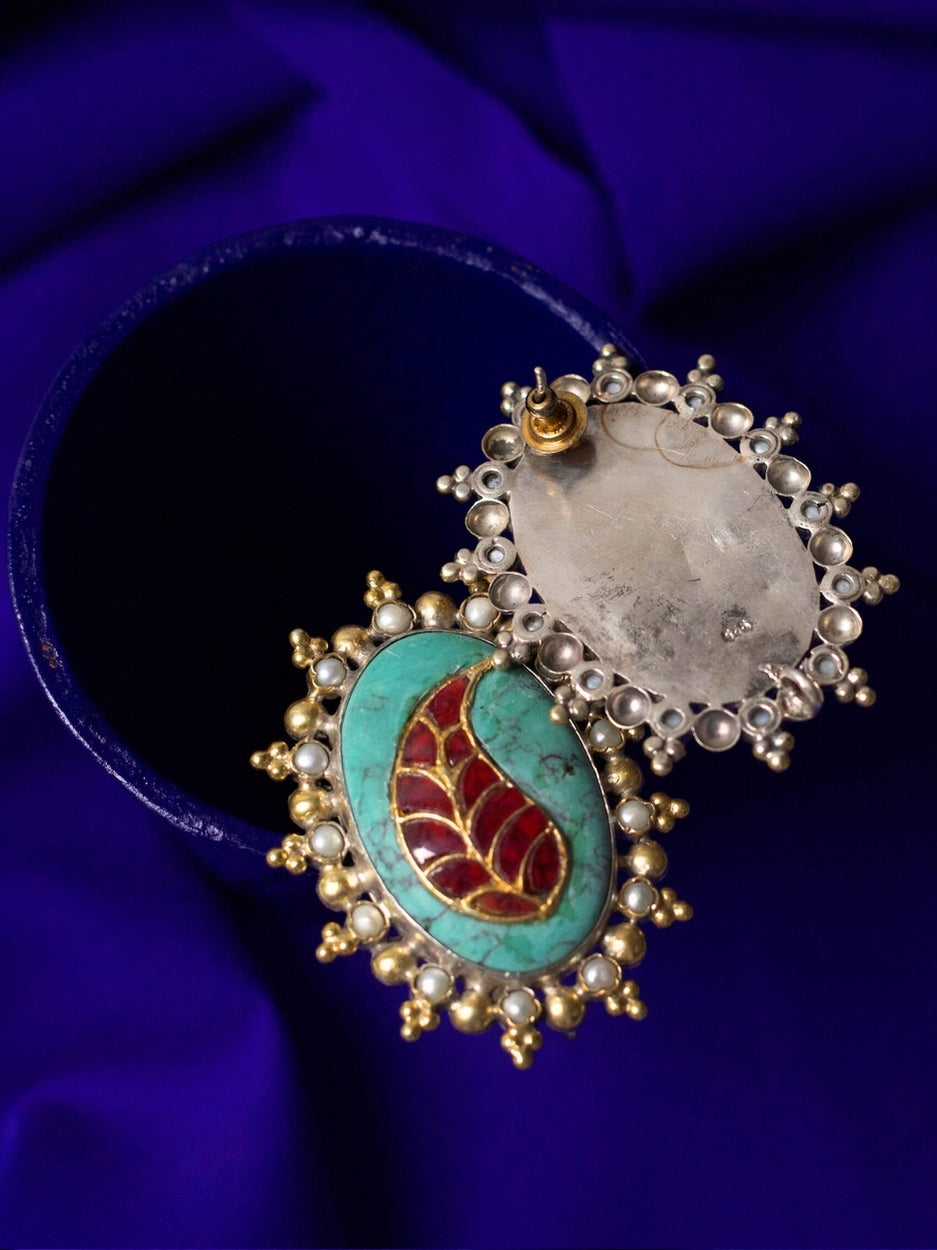 Close-up of a bold handcrafted 92.5 silver stud earring with red enamel leaf on turquoise stone, framed with pearls.