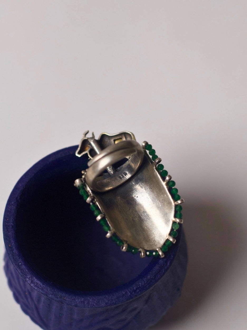 Close-up of handcrafted 92.5 silver ring with sculpted gold-tone bull, temple etching, red enamel leafwork, and green stone detail – Naksa Jewelry