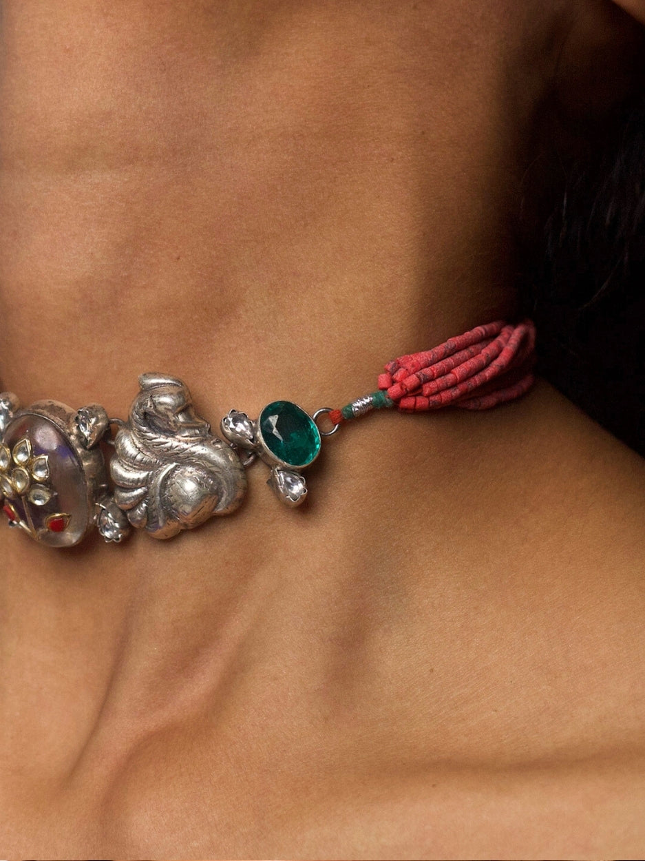 Close-up of She Who Blooms Silver Choker featuring oxidized silver floral motifs, central gemstone detail, and red thread tie-up, styled on model’s neck.
