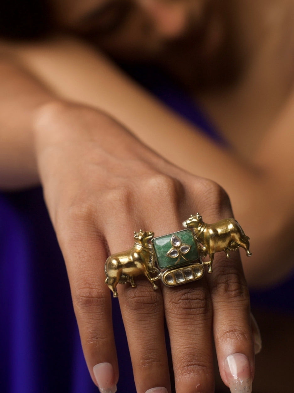 Close-up of handcrafted Dharohar Ring in pure 92.5 silver featuring twin golden cow motifs, kundan inlay, and green stone centerpiece