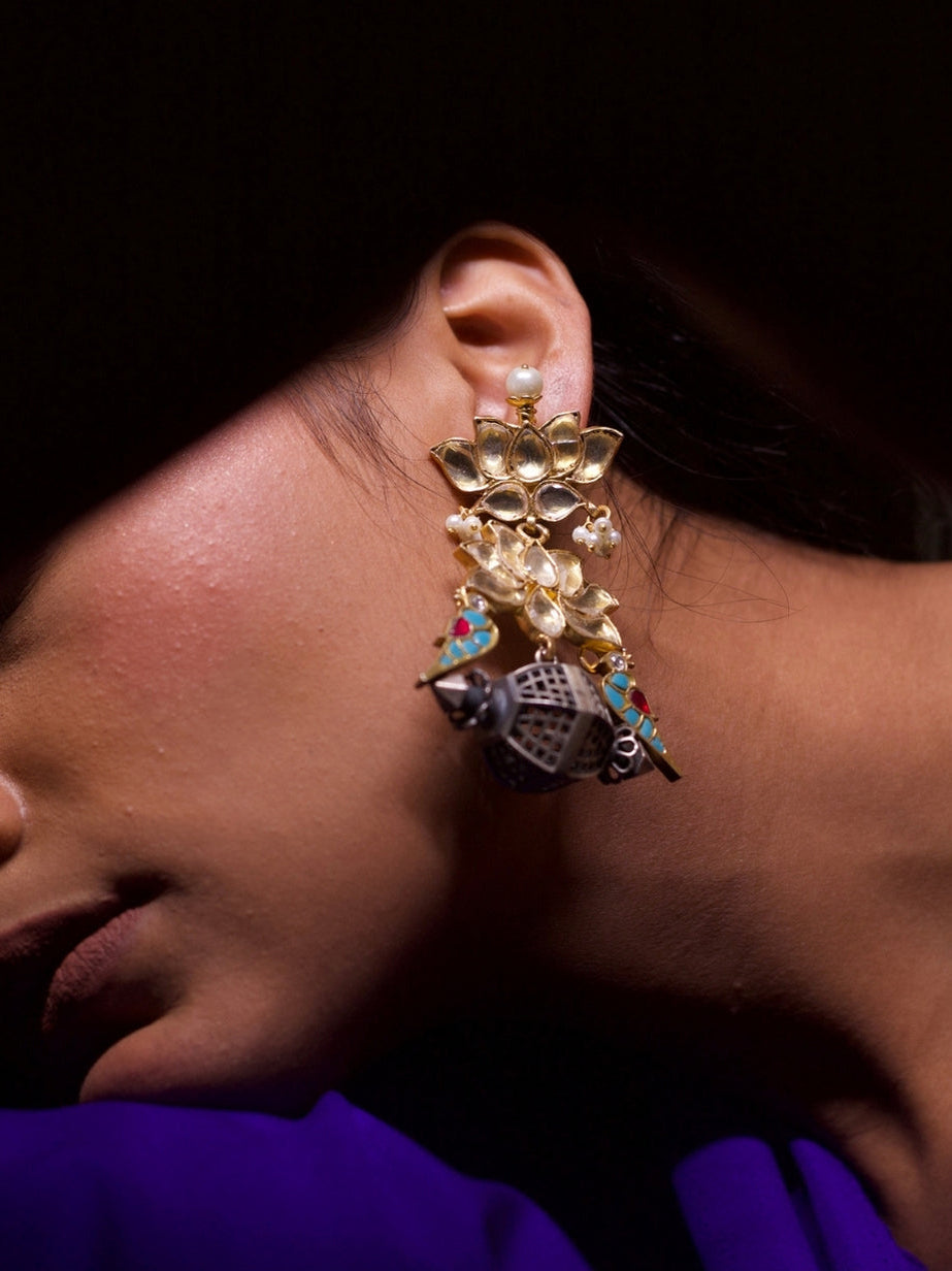 Close-up of handcrafted silver jhumkas with kundan lotus, colorful enamel parrots, and miniature silver dome inspired by jharokha windows – Naksa 92.5 silver earrings