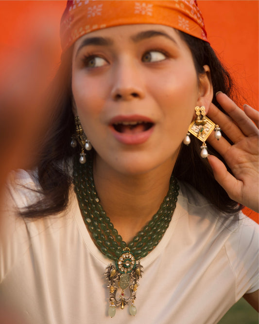 Four-strand green jade bead necklace in 925 silver with gold-plated kundan floral centre, twin bird motifs, carved jade drop, and decorative hanging elements.