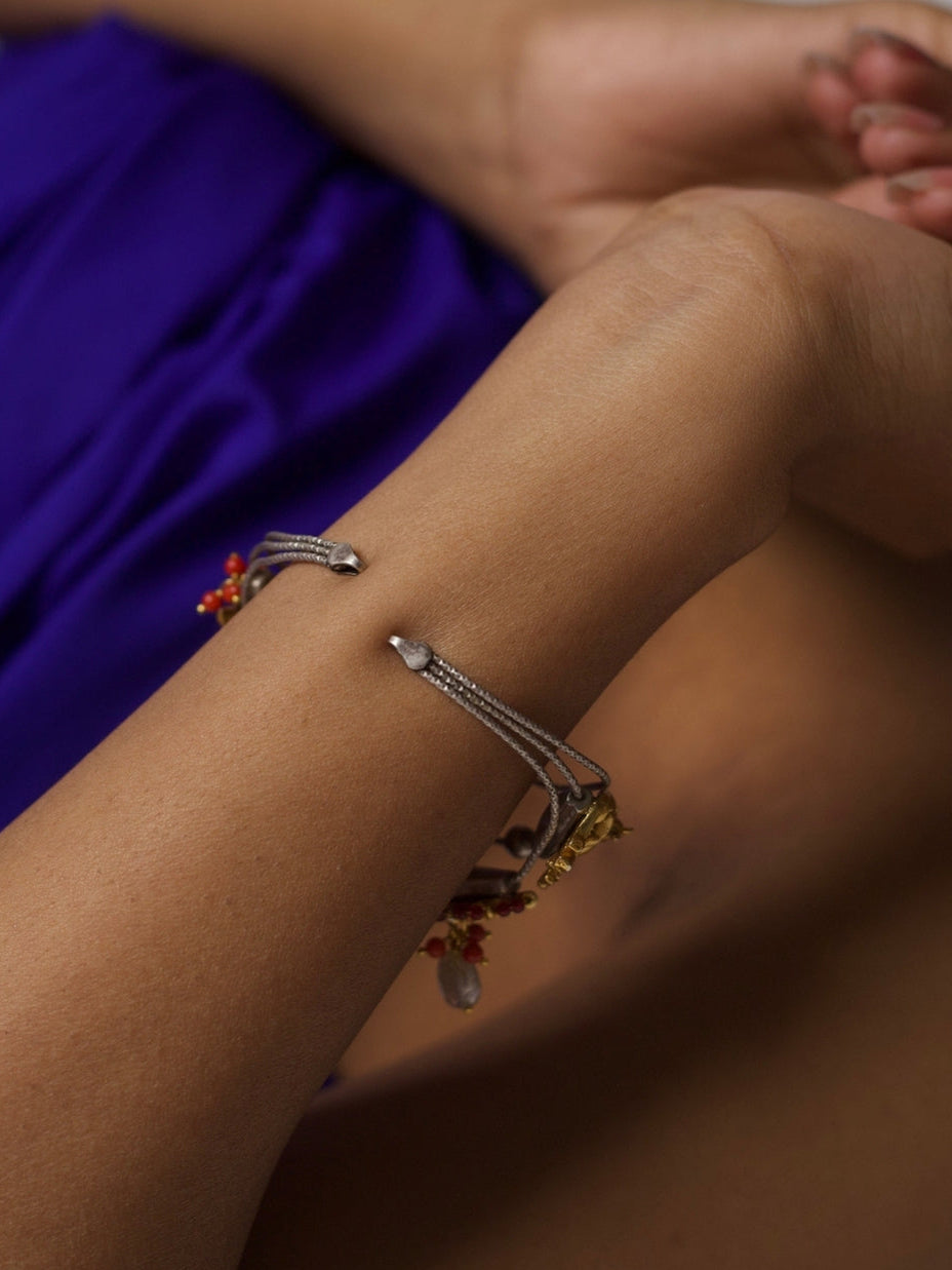 Handcrafted 92.5 silver bracelet with enamel folk charms, cow motif, and tribal bead detailing – styled on wrist against purple background.