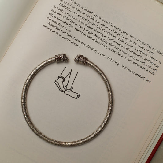 Two carved lionesses flank both sides of a sleek band etched with flowers and vines in this handcrafted traditional-modern silver anklet. This fusion of oxidised silver jewellery is an ode to the fierce spirit of women in the real and literary worlds. 