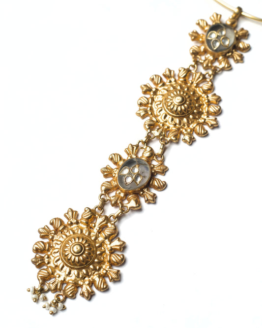 Close-up of sculpted solar rosette motifs with textured gold finish and kundan accents