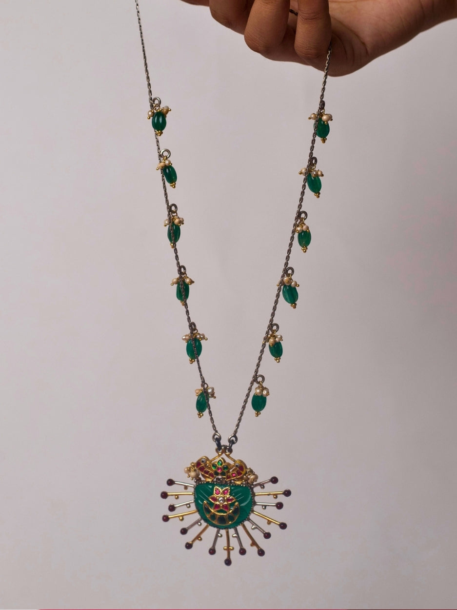 Close-up of Naksa's Dhoop Chhaon Necklace crafted in pure 92.5 silver, featuring a carved green pendant, dual-tone sun rays, and emerald green kharbooja drops with pearl accents.