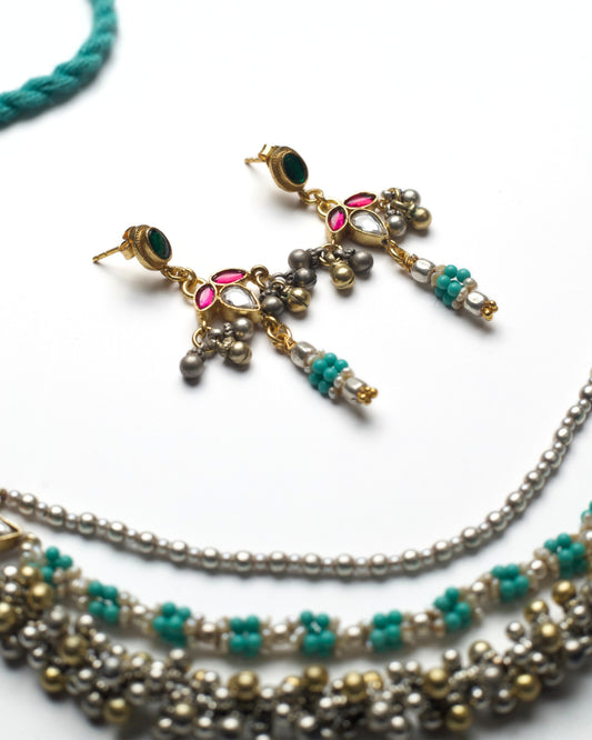 Close-up of silver earrings featuring kundan stones, turquoise bead clusters, and delicate ghungroo movement.