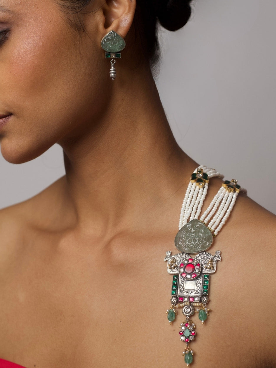 Five-strand Panchlada necklace in pure 92.5 silver with pearl beads, green carved stones, and a temple-style pendant featuring birds, moons, and intricate motifs. Styled with matching earrings.
