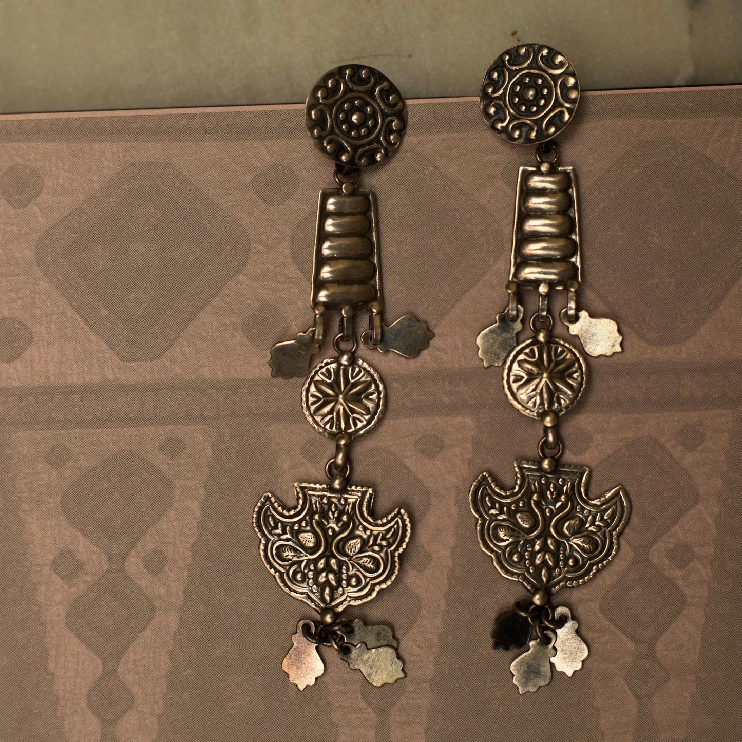 These dangling tiered earrings resemble an enchanting ladder out of a fairytale reaching for the moon. This fusion silver jewellery piece s intricately embossed with nature-inspired motifs and is lightweight and durable.
