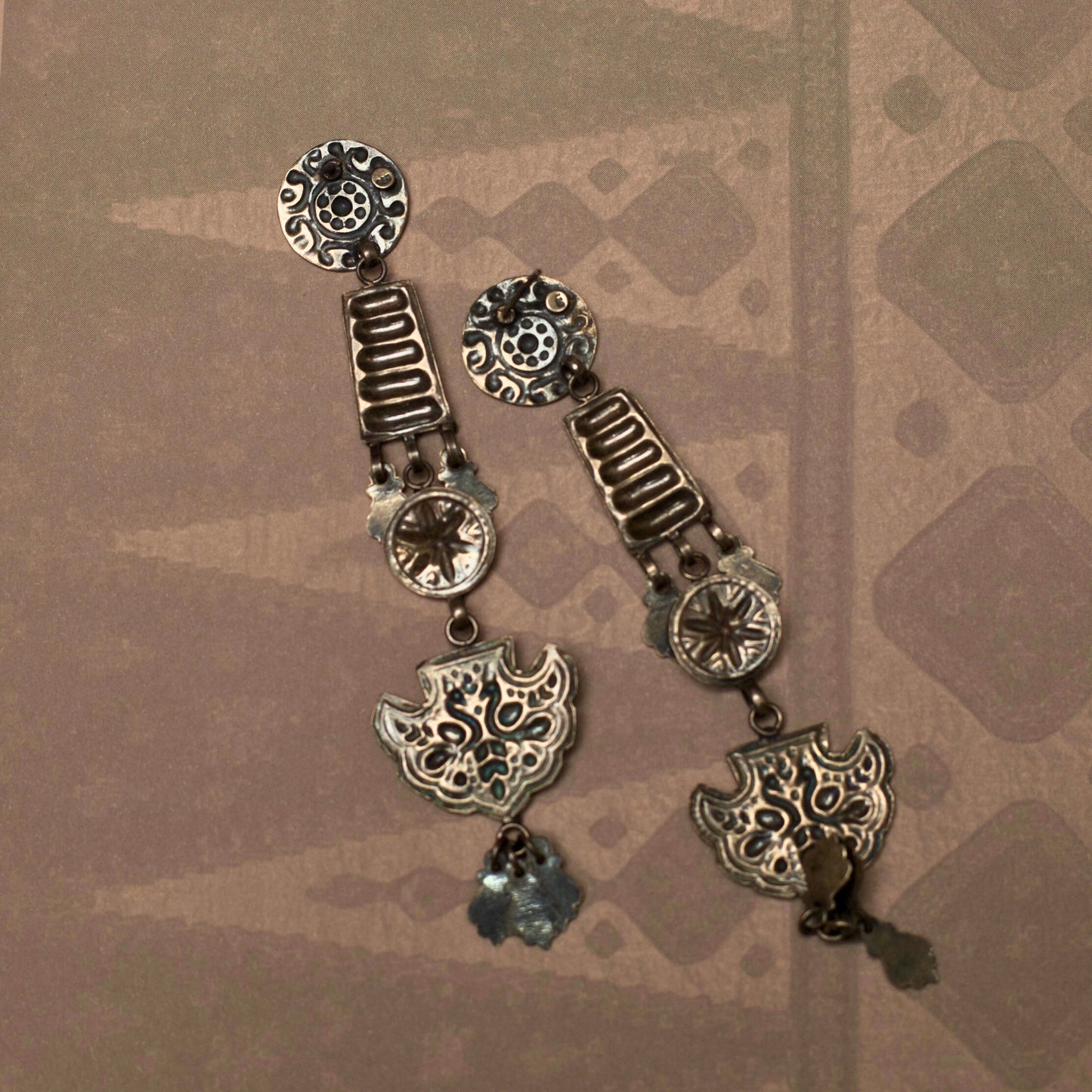 These dangling tiered earrings resemble an enchanting ladder out of a fairytale reaching for the moon. This fusion silver jewellery piece s intricately embossed with nature-inspired motifs and is lightweight and durable.