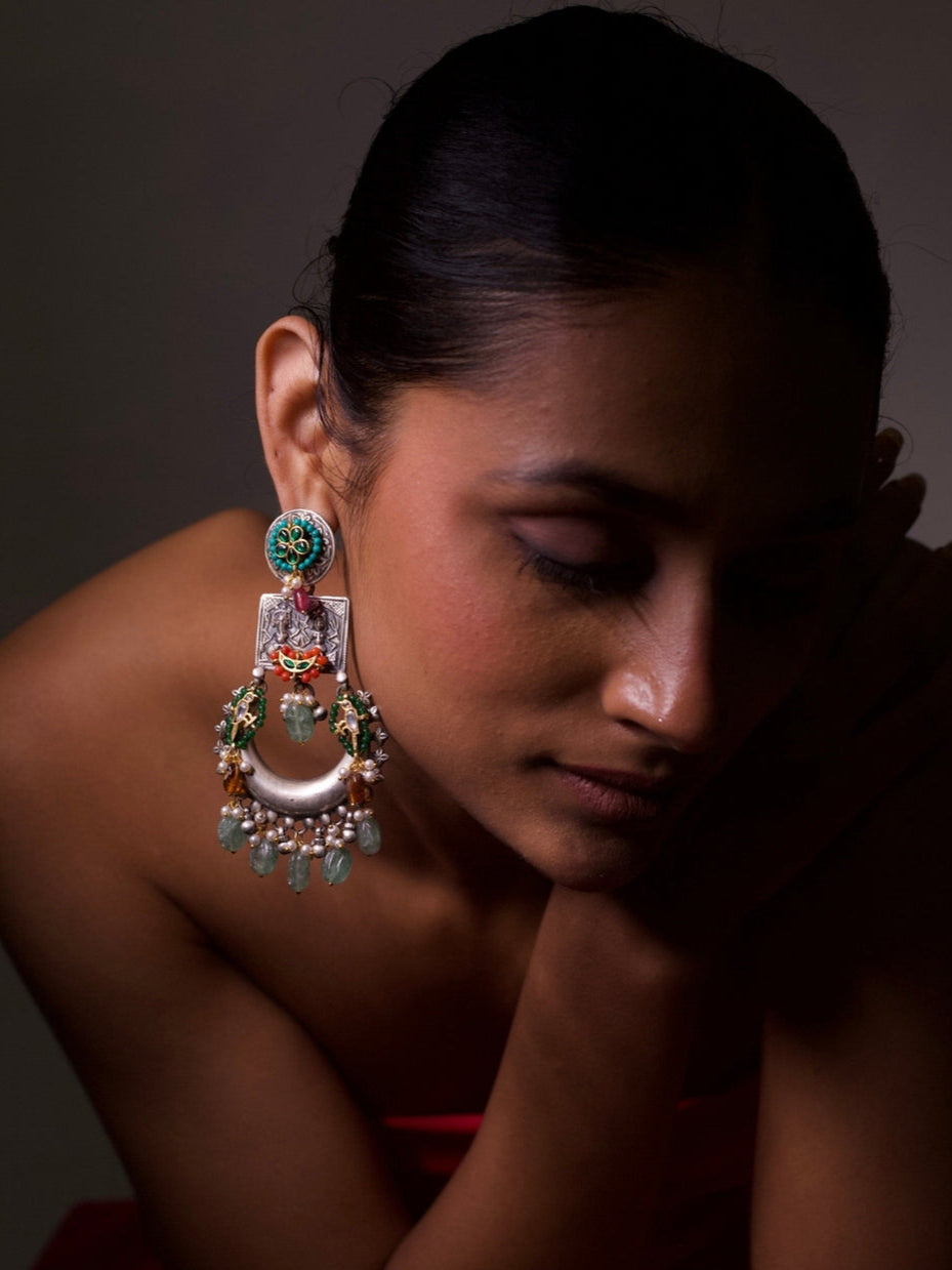 Close-up of Naksa’s Prachin Pakshi Chaandbaalis in pure silver, featuring tribal carvings, floral enamel, golden birds, gemstone drops, and crescent motifs.