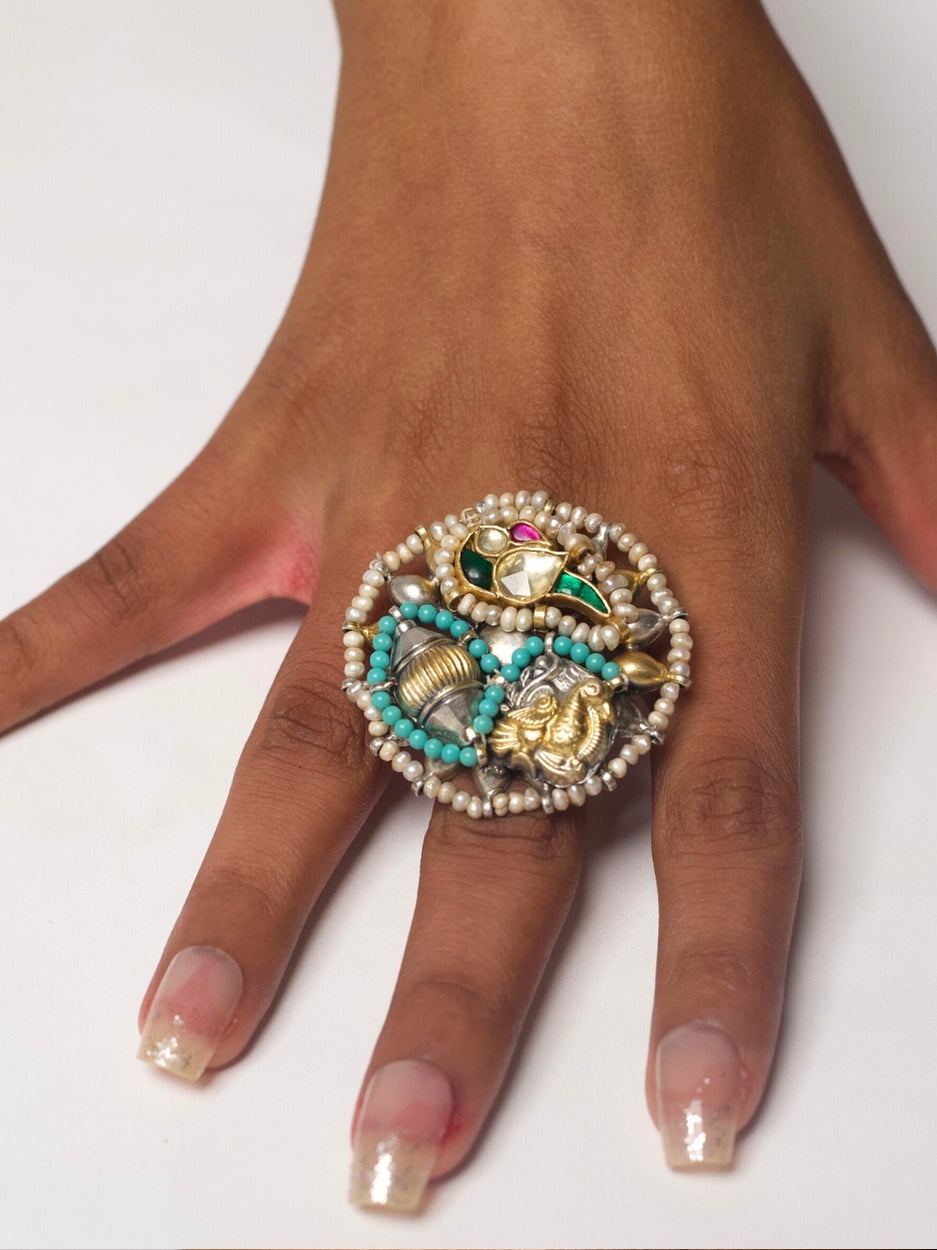 Hand wearing Royal Medley Ring crafted in 92.5 silver with kundan peacock, golden shankh, elephant, and parrot motifs, surrounded by pearls and turquoise beads