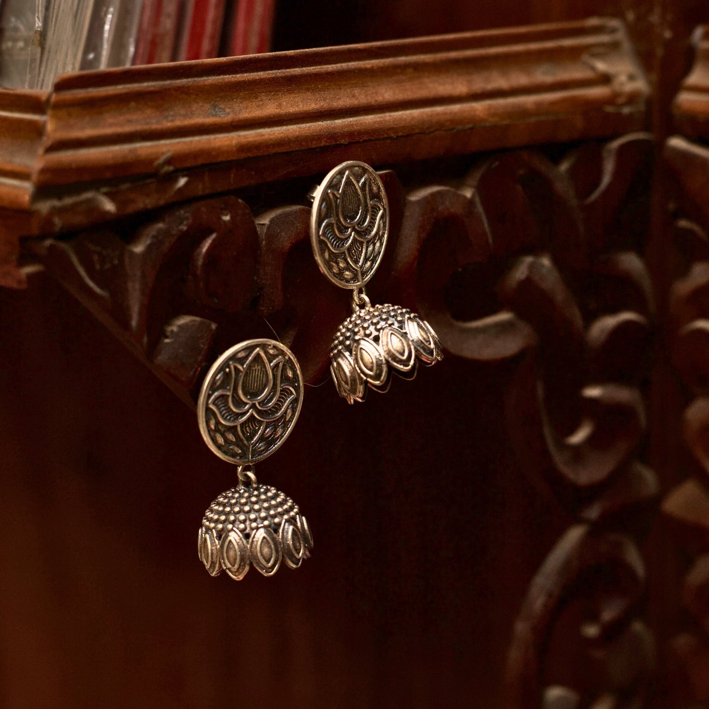 Lotuses are multi-layered just like outstanding pieces of literature. Jazz up your everyday outfits with these lightweight oxidised silver jhumkas with lotus motifs and a classic dome dangler. 