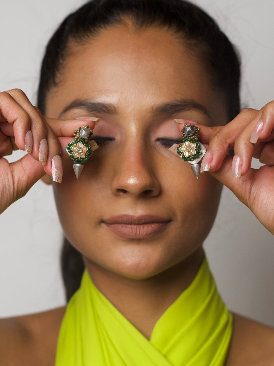 Close-up of Sutli Bomb Earrings in pure 92.5 silver with green beaded kundan floral motif and spike-end design