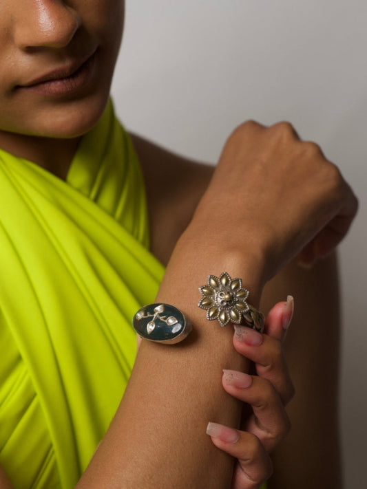 Close-up of Green Glint Silver Cuff in 92.5 silver with gold-detailed flower and green enamel branch motif, worn on wrist