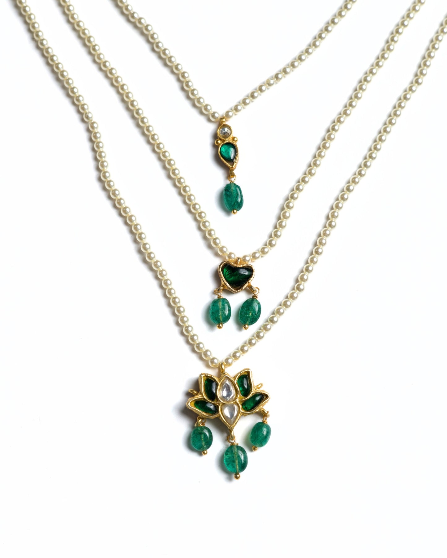 Three-layered 925 silver pearl necklace with emerald heart detail and lotus-inspired kundan pendant with green stone drops.