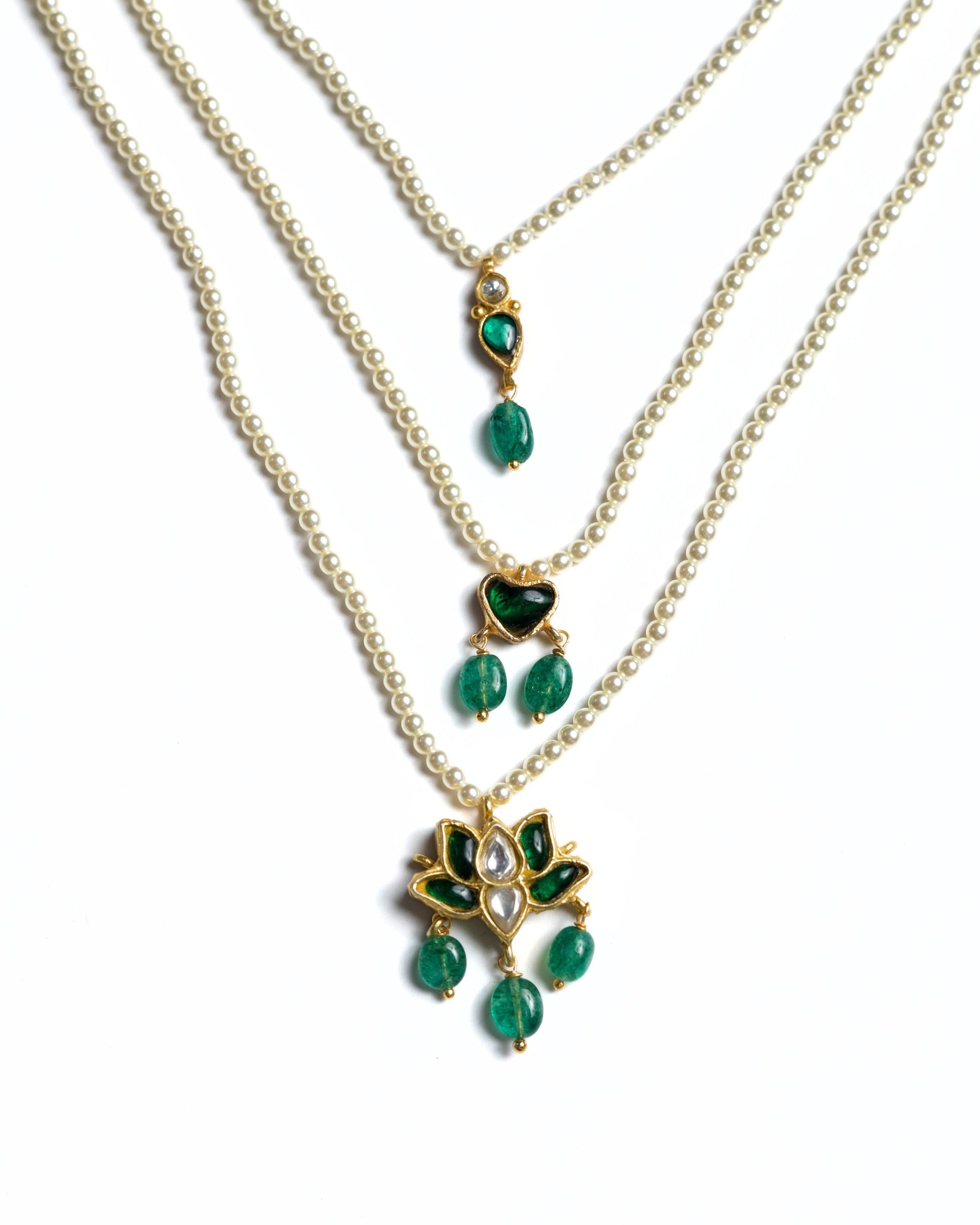 Three-layered 925 silver pearl necklace with emerald heart detail and lotus-inspired kundan pendant with green stone drops.