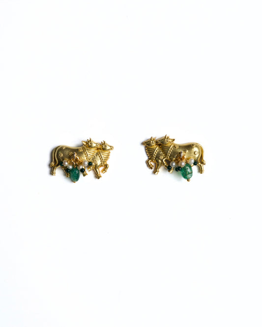 Close-up of gold-polished 925 silver cow motif stud earrings with pearl clusters and green stone drops on a white background.
