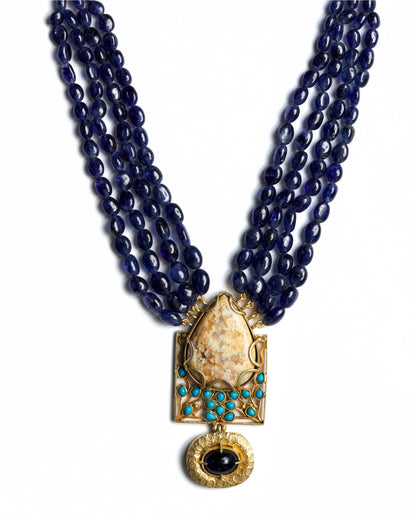 Four-strand indigo bead necklace in 925 silver with large marbled stone pendant, turquoise accents, and hammered gold drop detail.