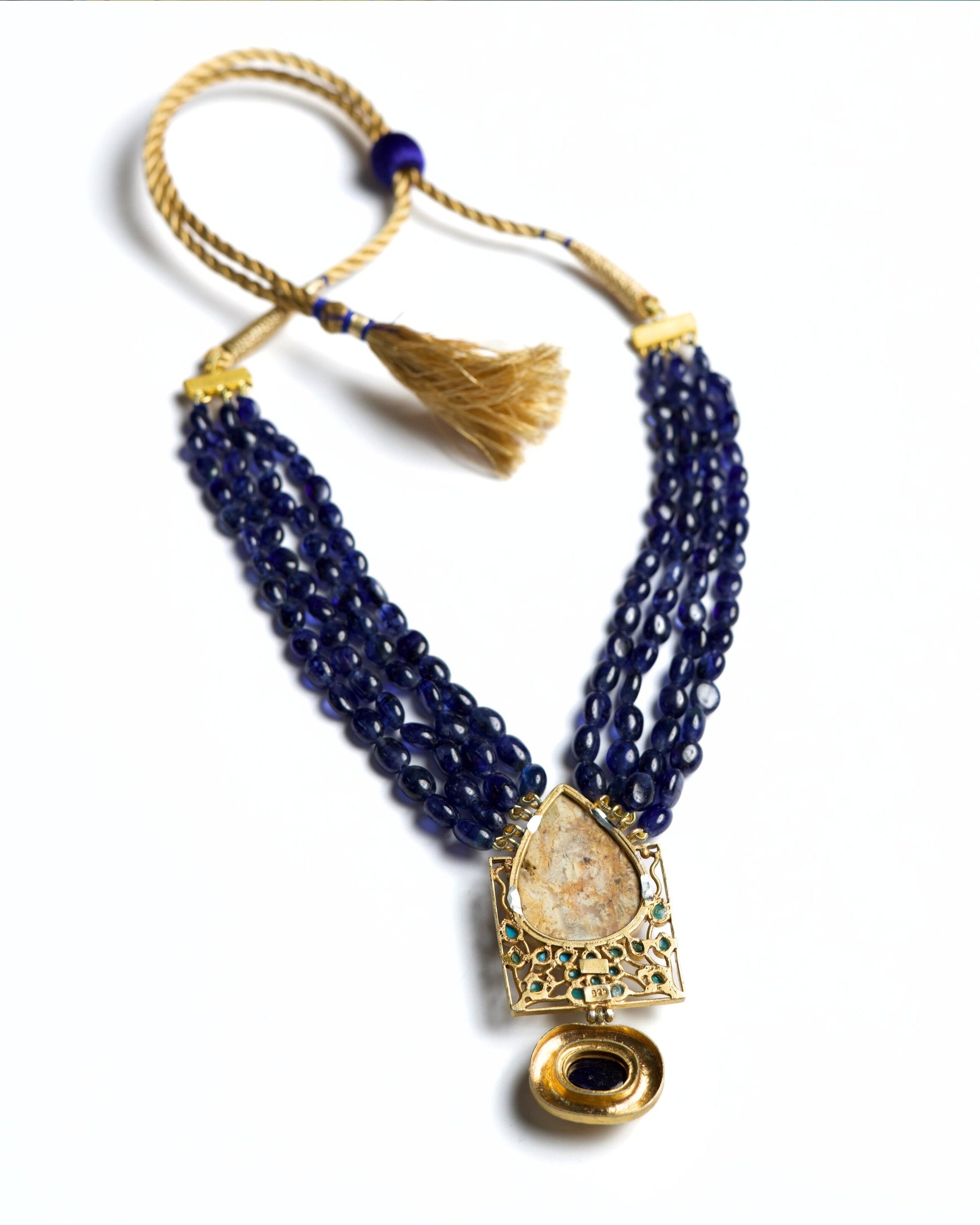 Four-strand indigo bead necklace in 925 silver with large marbled stone pendant, turquoise accents, and hammered gold drop detail.