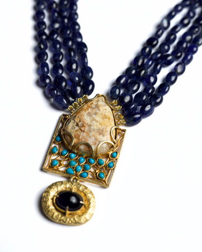 Four-strand indigo bead necklace in 925 silver with large marbled stone pendant, turquoise accents, and hammered gold drop detail.