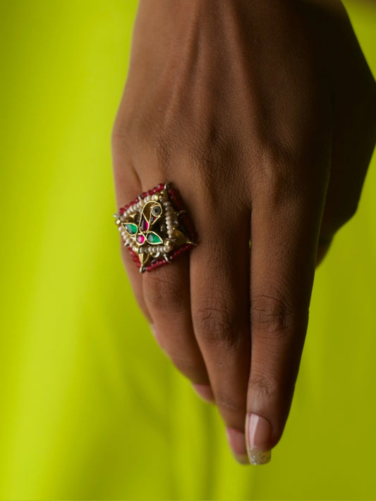 Close-up of Desi Disco Ring in 92.5 silver featuring vibrant bird motif with red and green enamel, pearls, and a bold square design worn on hand.