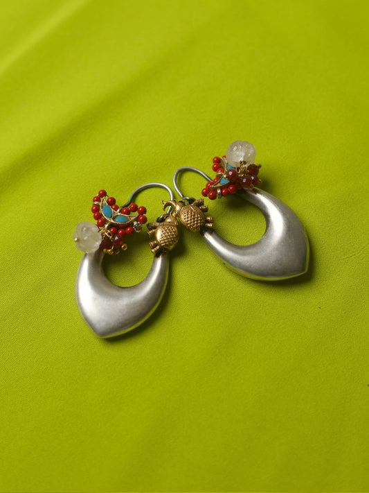 Elongated heart-shaped silver hoop earrings with golden elephant motifs, red beads, turquoise accents, and a white gemstone – Naksa