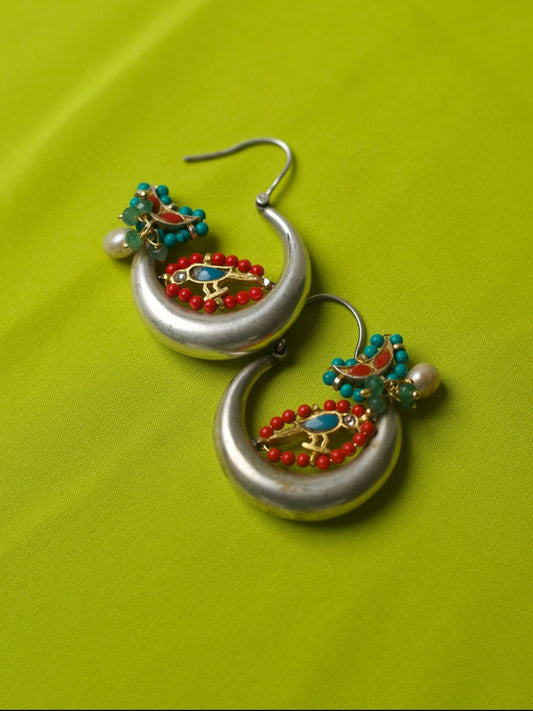 Pair of circular 92.5 silver hoop earrings with gold parrot motif, red and turquoise beads, pearl accent, and enamel detail