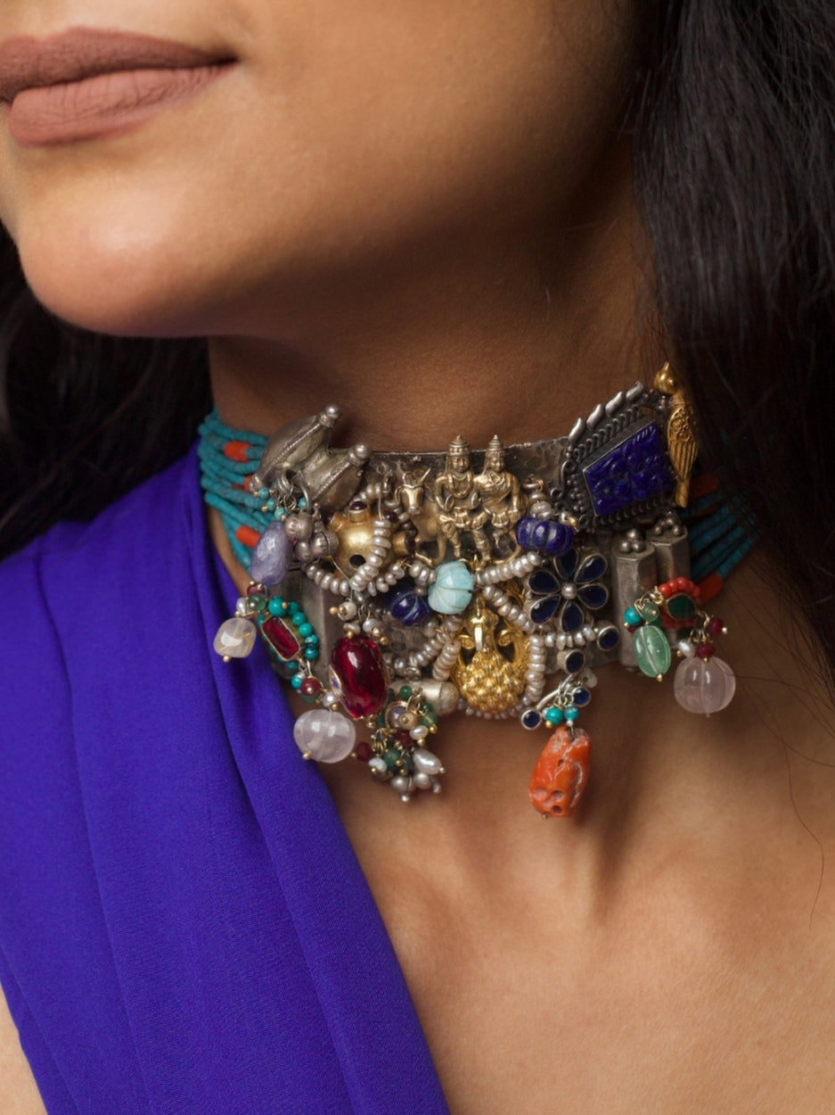 Close-up of a handcrafted 92.5 silver choker with temple and goddess motifs, red and green stonework, gold accents, and layered pearl strands.