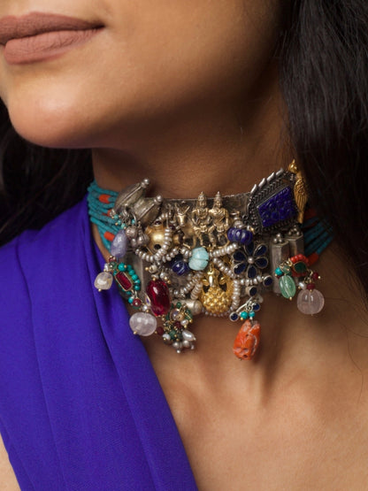 Close-up of a handcrafted 92.5 silver choker with temple and goddess motifs, red and green stonework, gold accents, and layered pearl strands.