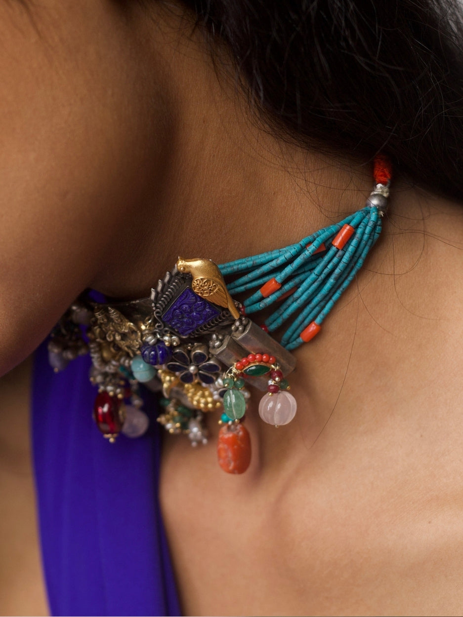 Close-up of a handcrafted 92.5 silver choker with temple and goddess motifs, red and green stonework, gold accents, and layered pearl strands.